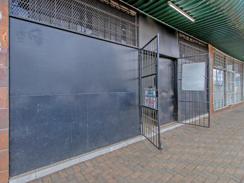 Commercial storefront featuring a security gate, metal grille, and corrugated awning, providing a functional entrance for a retail or office space.