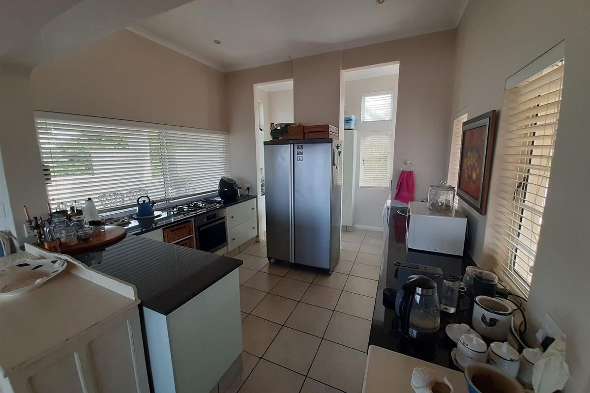 Functional kitchen featuring granite countertops, built-in oven, gas hob, and tiled flooring, with ample natural light provided by multiple windows.