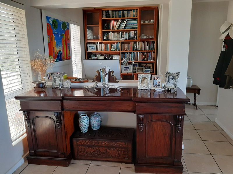 A living area featuring a large built-in wooden bookshelf and neutral tiled flooring, providing a functional space with integrated storage solutions.