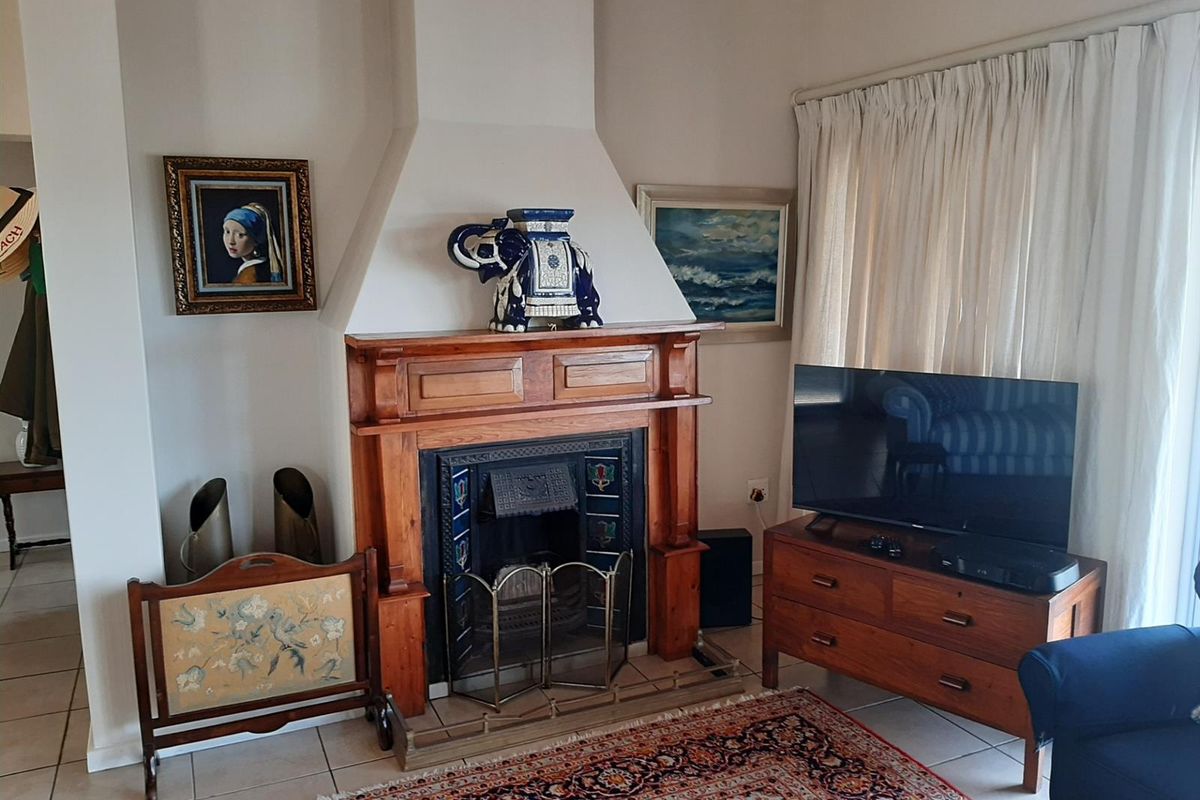 A cozy living room featuring a traditional wooden fireplace mantelpiece and tiled flooring, providing a warm and classic focal point for the space.