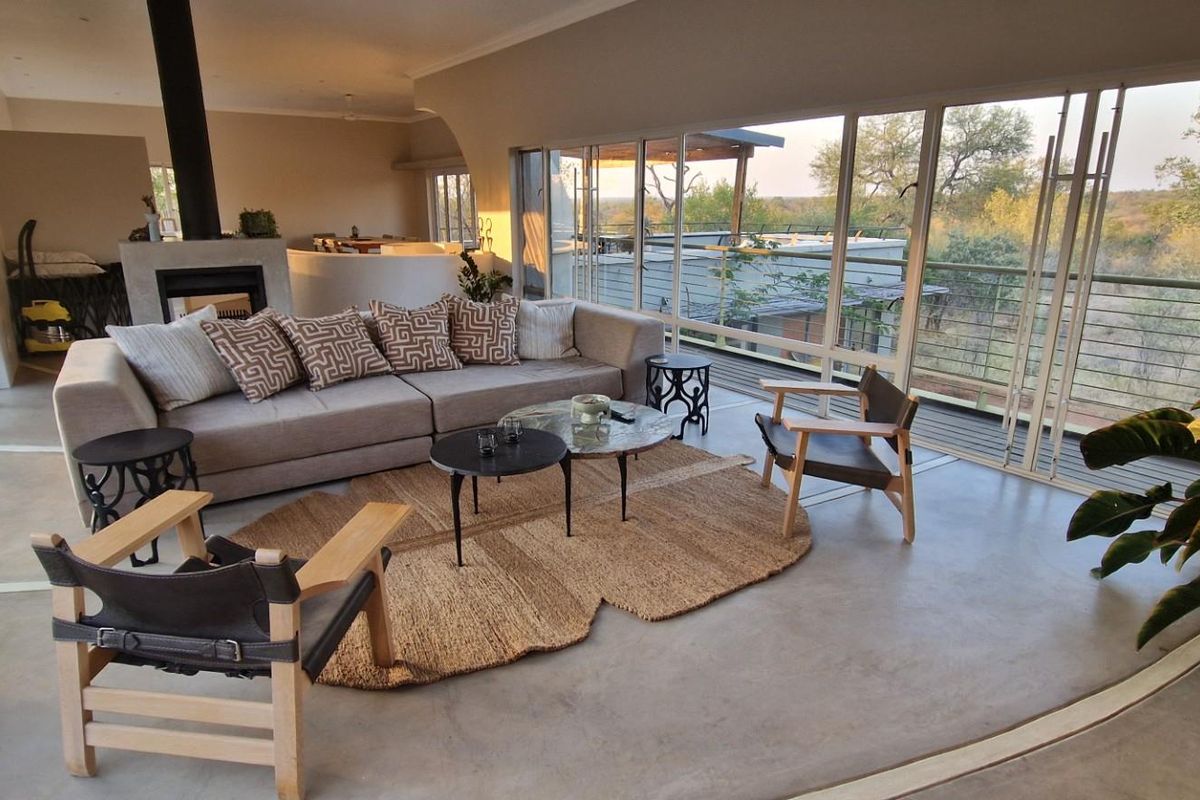 Spacious open-plan living area featuring polished concrete floors, a modern fireplace, and expansive sliding glass doors offering scenic outdoor views.