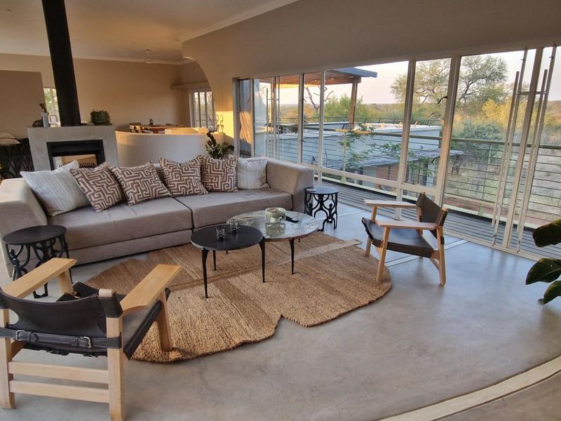 Spacious open-plan living area featuring polished concrete floors, a modern fireplace, and expansive sliding glass doors offering scenic outdoor views.