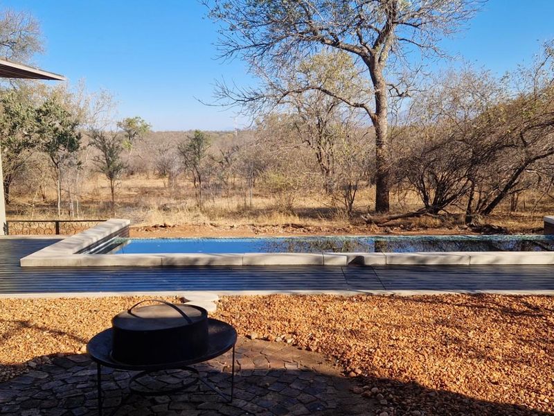 Outdoor pool area featuring a rectangular swimming pool with stone coping, timber decking, and direct access to the home via large glass sliding doors.