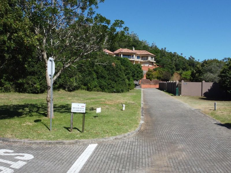 A view of the paved access road leading towards the residential property, surrounded by established trees and landscaped greenery.