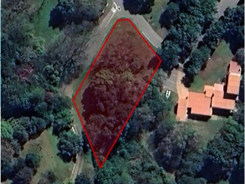 Aerial view of a vacant residential plot highlighted in red, situated in a well-established, tree-lined neighborhood.