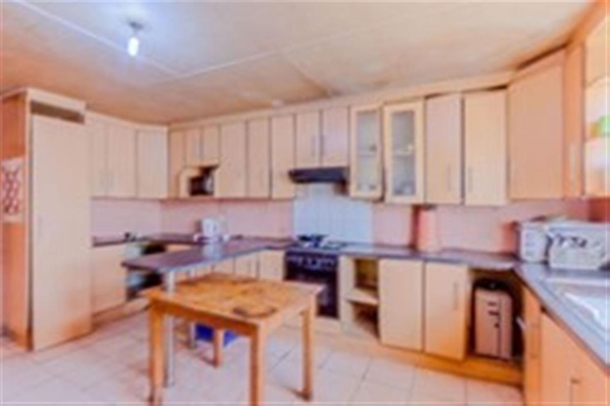 A dated kitchen featuring built-in cabinetry, an integrated oven and hob, and tiled flooring, offering potential for a modern renovation.
