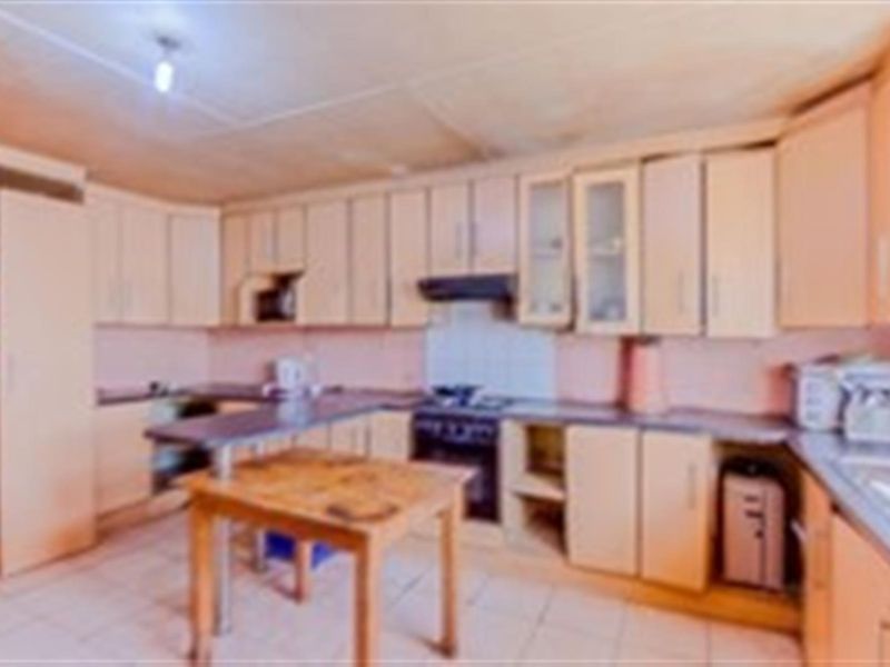 A dated kitchen featuring built-in cabinetry, an integrated oven and hob, and tiled flooring, offering potential for a modern renovation.