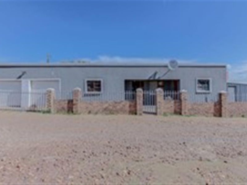 Front elevation of a single-story house featuring a brick boundary wall, metal security fencing, and a double garage.