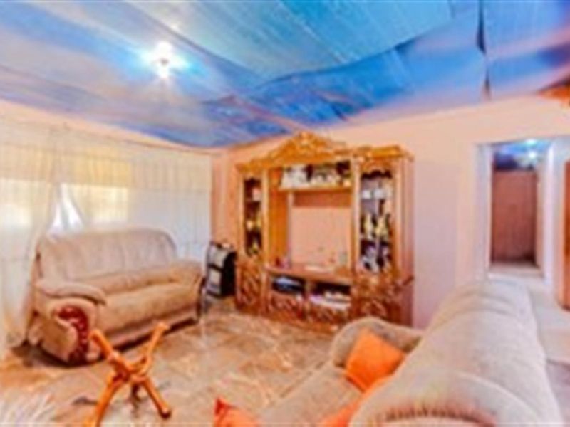 A living room featuring tiled flooring and a non-standard ceiling finish, requiring cosmetic updates to improve the overall aesthetic and condition.