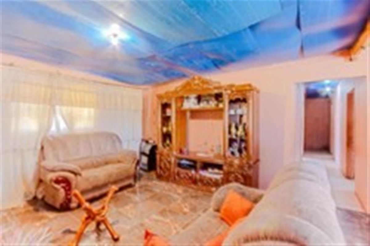 A living room featuring tiled flooring and a non-standard ceiling finish, requiring cosmetic updates to improve the overall aesthetic and condition.