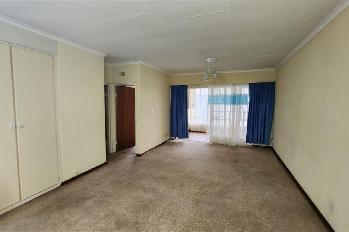 A spacious, empty living room featuring neutral walls, built-in storage cupboards, and sliding glass doors leading to an outdoor area.