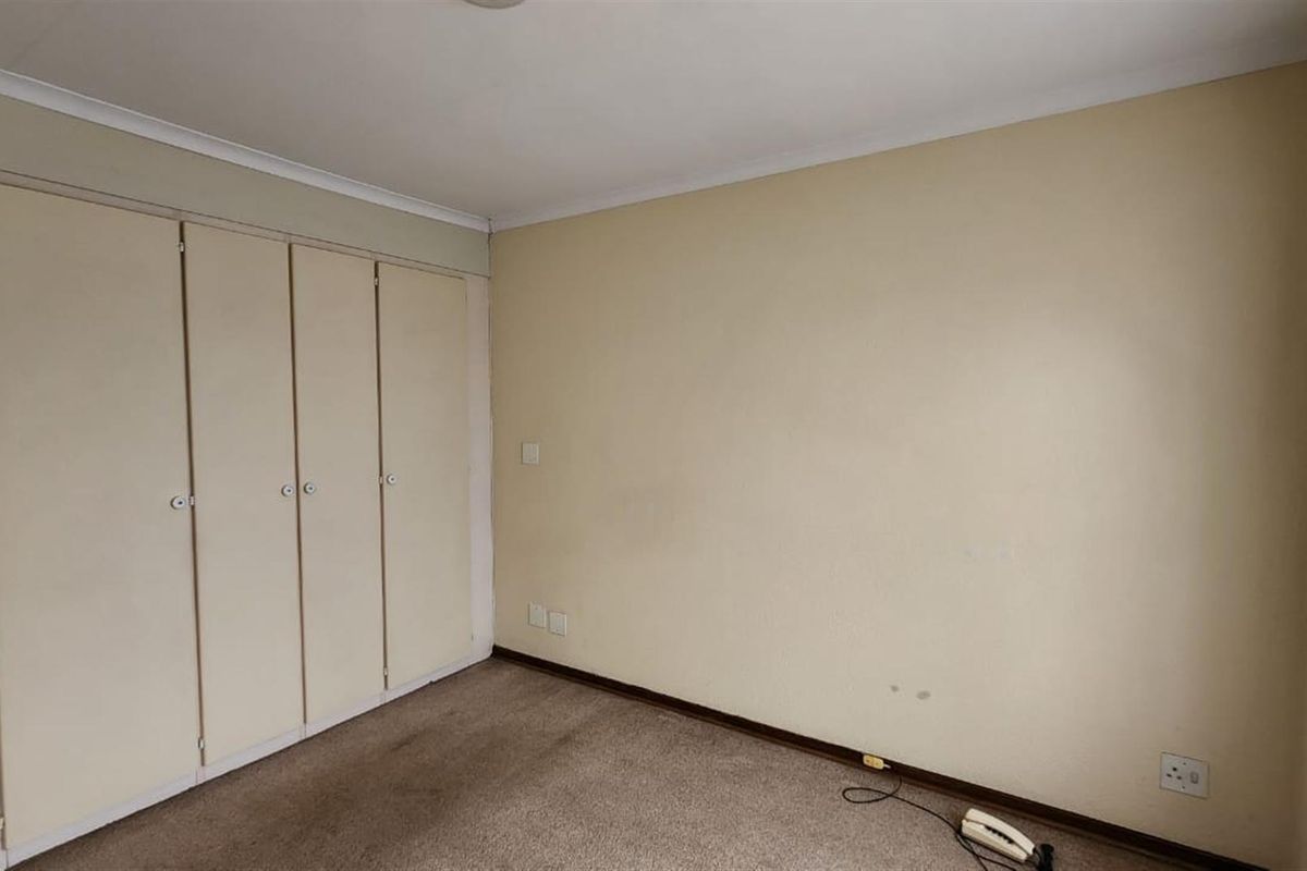 A vacant bedroom featuring built-in wardrobes, neutral wall finishes, and carpeted flooring, offering a blank canvas for personalization.