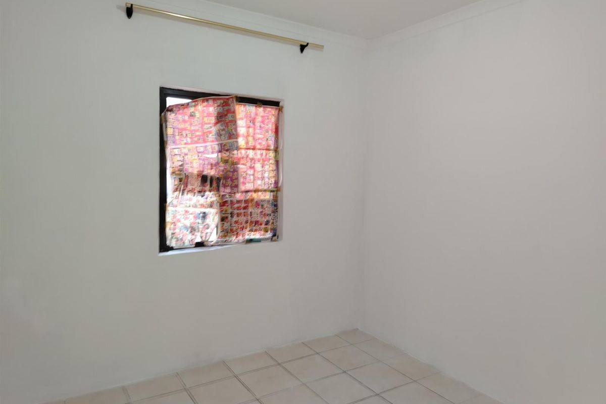 A clean, empty bedroom featuring neutral white walls, tiled flooring, and a curtain rod, ready for personalization.