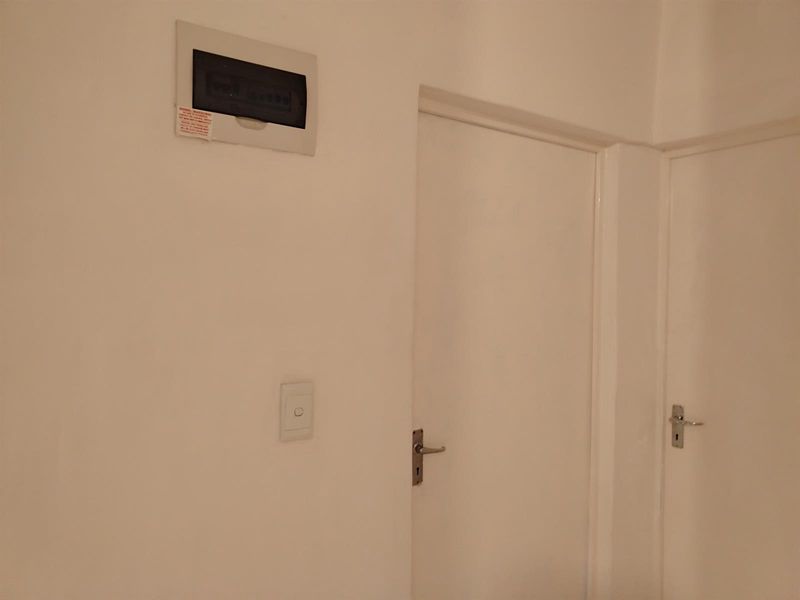 A view of a hallway featuring a wall-mounted electrical distribution board and two interior doors.