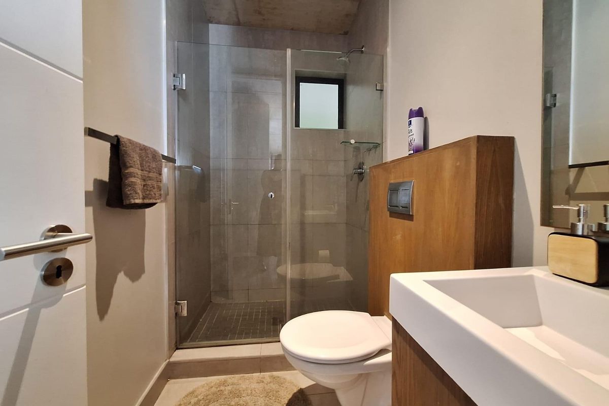 Modern bathroom featuring a glass-enclosed walk-in shower, wall-mounted toilet with concealed cistern, and a contemporary vanity unit.