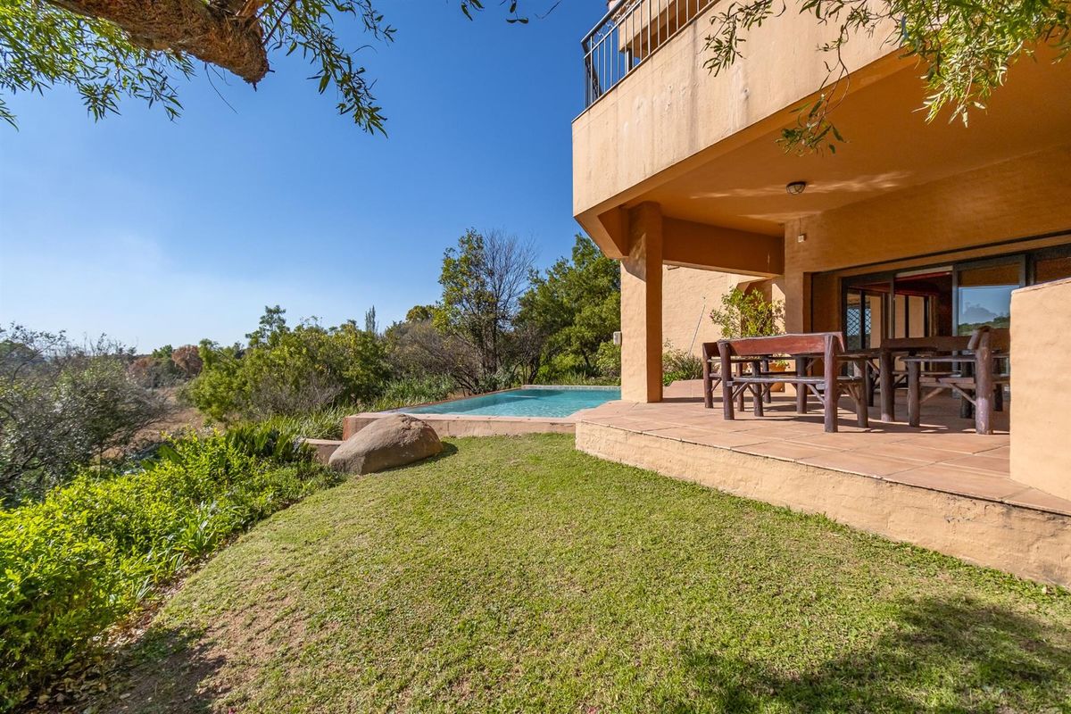 Rear view of the property featuring a covered patio, swimming pool, and landscaped garden area with scenic views.