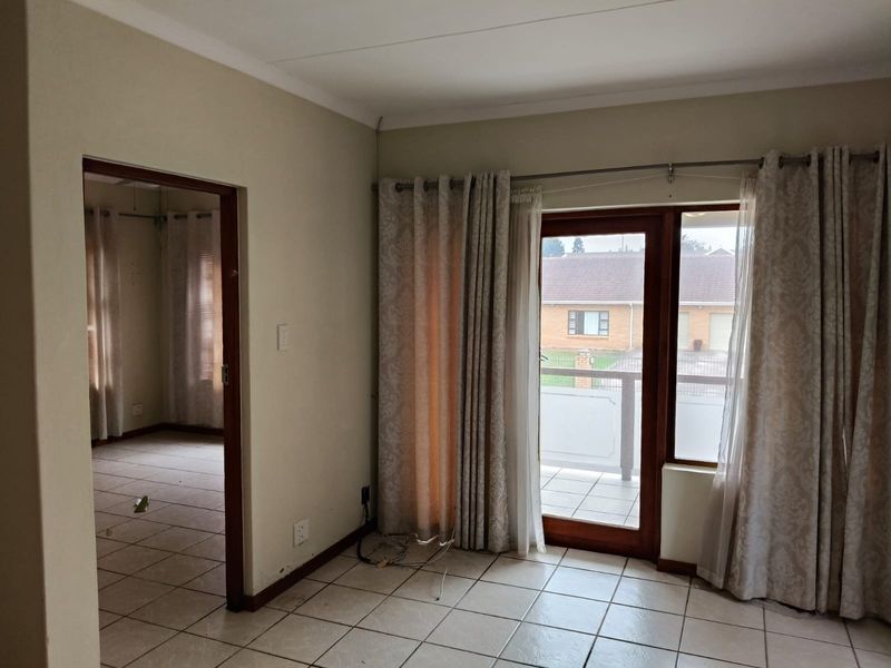 An empty living area featuring tiled flooring and direct access to a balcony through a sliding glass door.