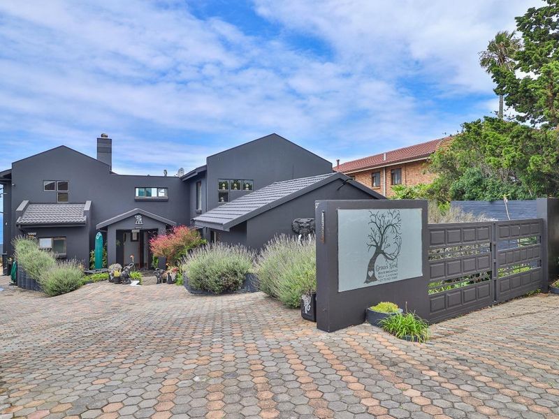Front elevation of a modern dark-painted house featuring a paved driveway, secure gated entrance, and well-maintained exterior finishes.