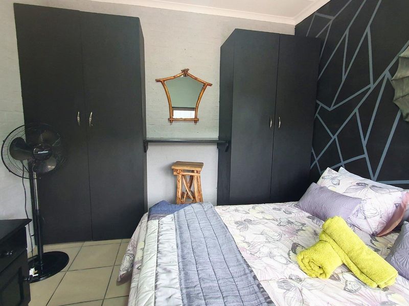 A bedroom featuring built-in cupboards and tiled flooring, with a decorative accent wall.