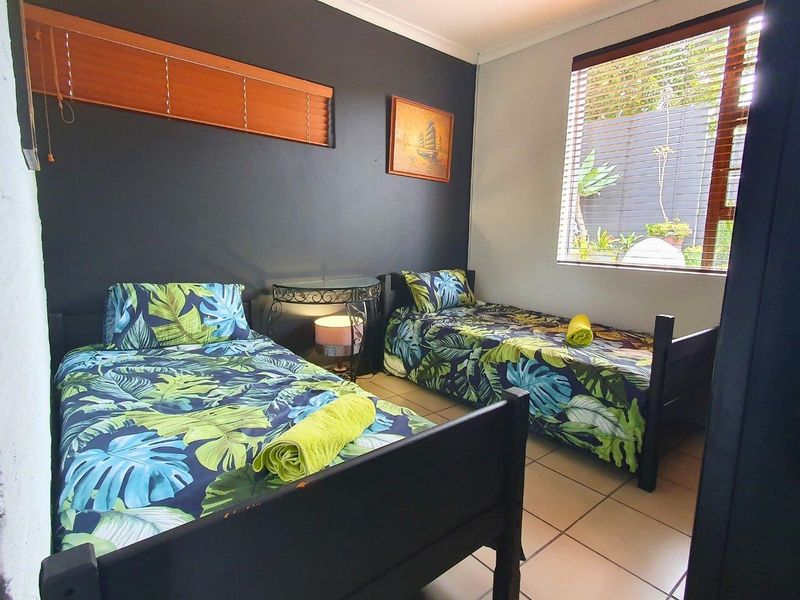 A bedroom featuring tiled flooring and venetian blinds, providing a functional space with neutral wall finishes.