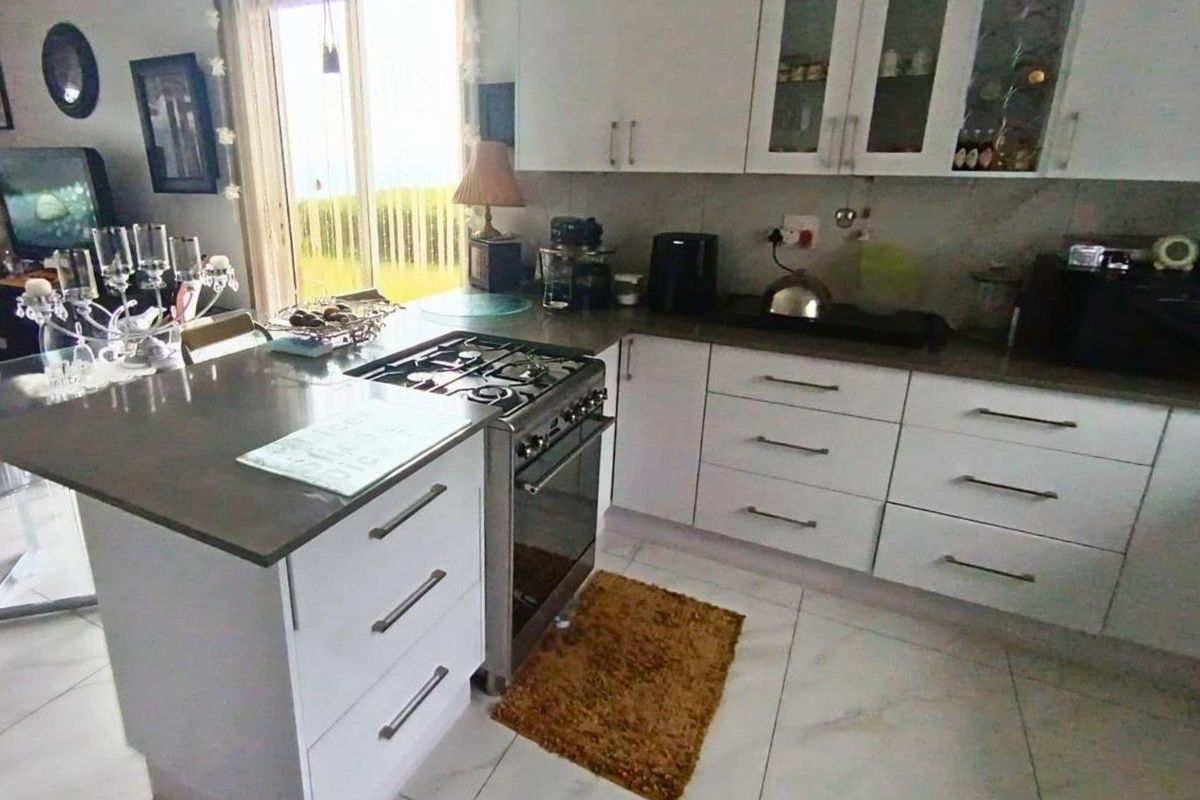 Modern kitchen featuring white cabinetry, stone countertops, a gas stove, and tiled flooring with direct access to the outdoor area.