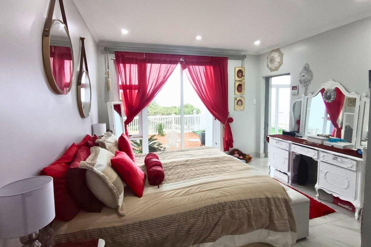 Spacious bedroom featuring tiled flooring, recessed ceiling lighting, and large sliding glass doors providing direct access to the outdoor patio area.