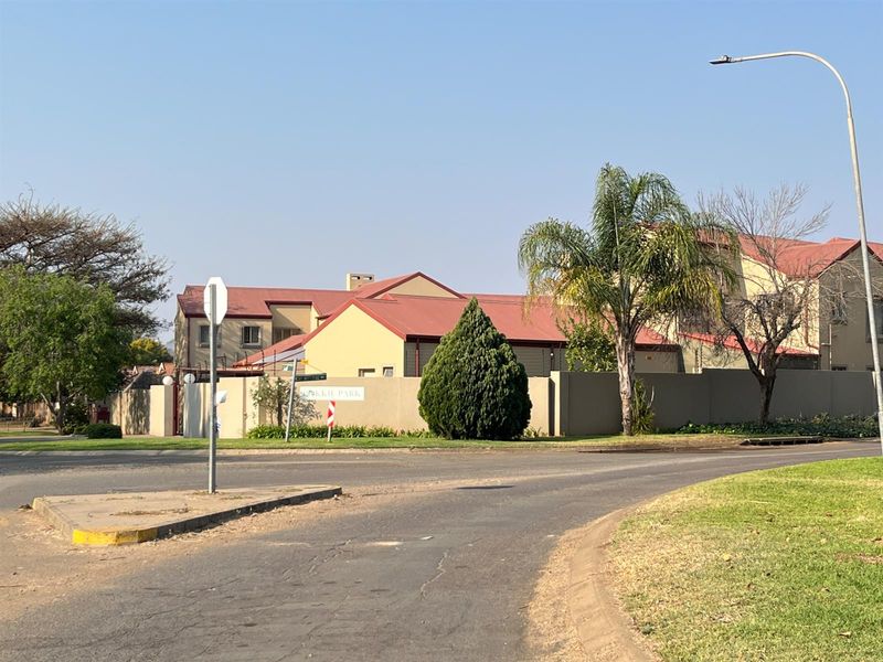 Street view of the apartment complex exterior, featuring perimeter walling, electric fencing, and pitched metal roofing.