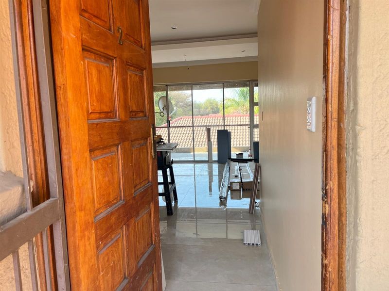 An entry hallway leading into an open plan living area with large sliding glass doors and tiled flooring throughout.