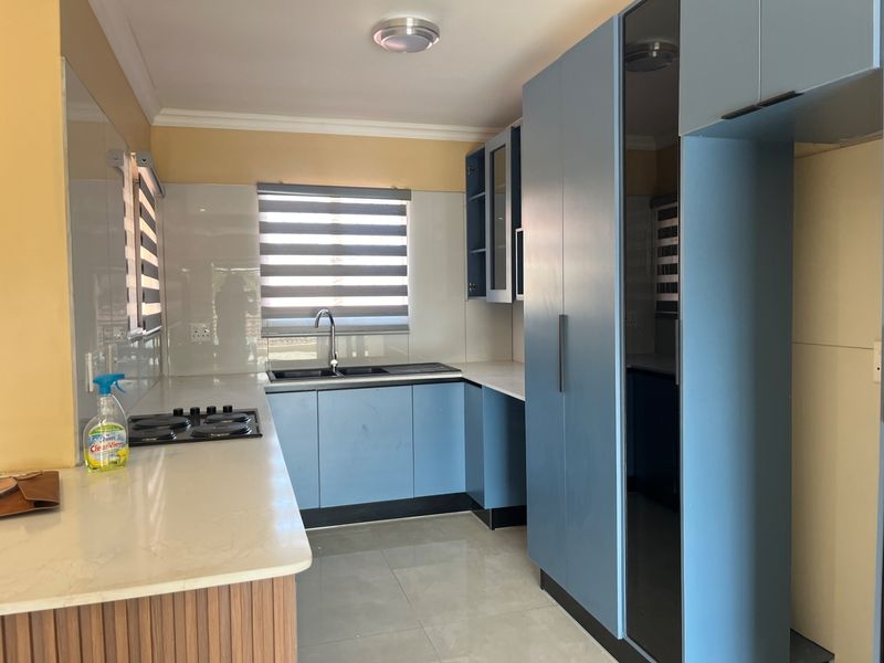 Modern kitchen featuring blue built-in cabinetry, stone countertops, a double sink, and a built-in hob with a tiled backsplash.