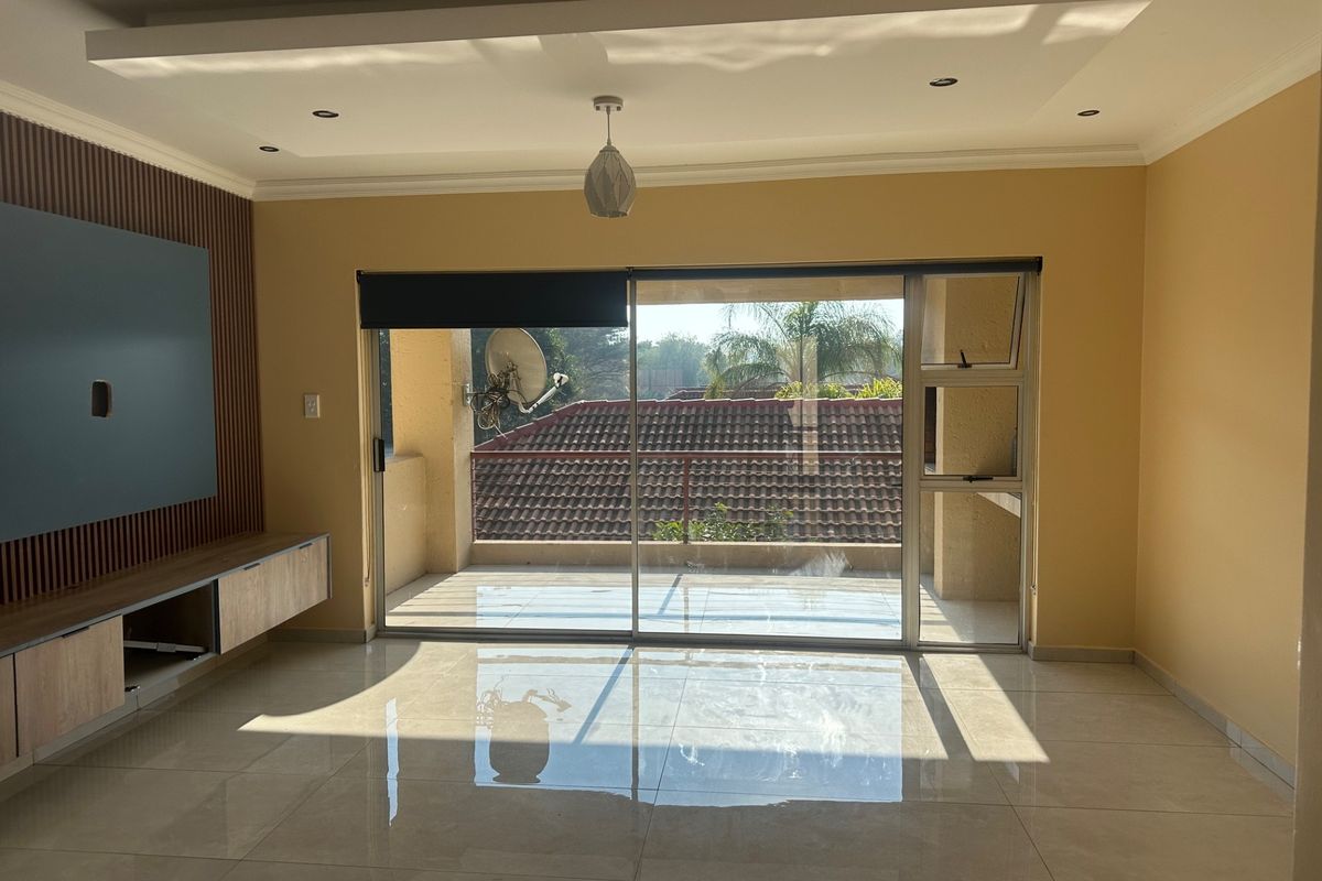 Spacious living room featuring polished tile floors, a modern slatted wood feature wall with built-in cabinetry, and large sliding doors opening to a balcony.