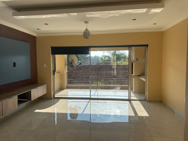 Spacious living room featuring polished tile floors, a modern slatted wood feature wall with built-in cabinetry, and large sliding doors opening to a balcony.