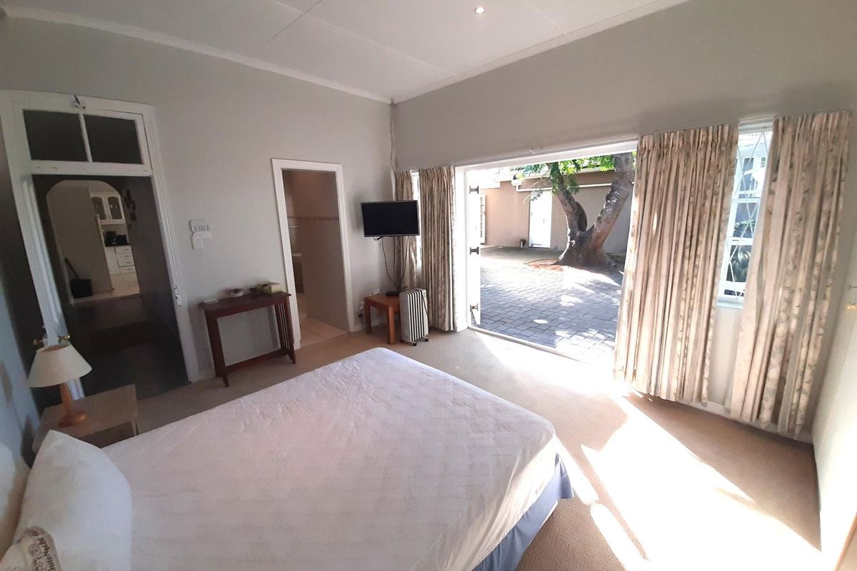Spacious bedroom featuring neutral walls, carpeted flooring, and large sliding glass doors providing direct access to a paved outdoor courtyard area.