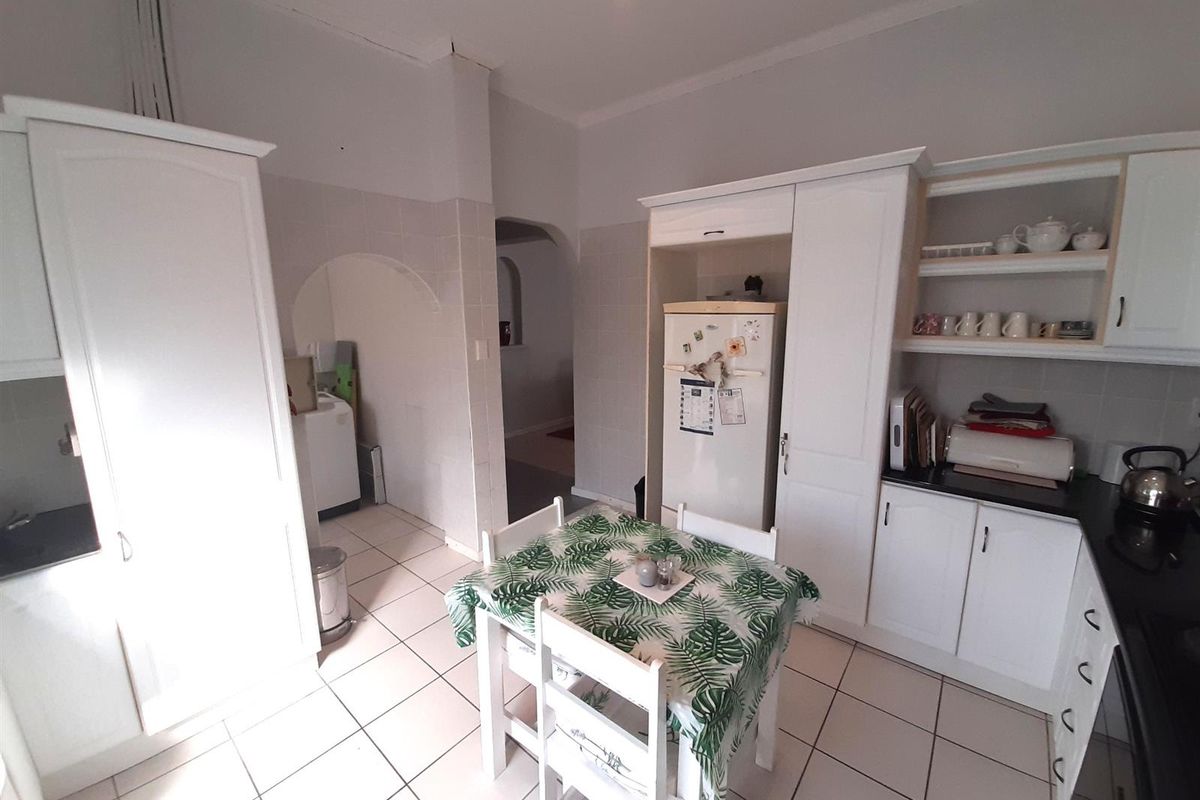 A functional kitchen featuring white cabinetry, tiled flooring, and an arched entryway leading to a separate utility or laundry area.