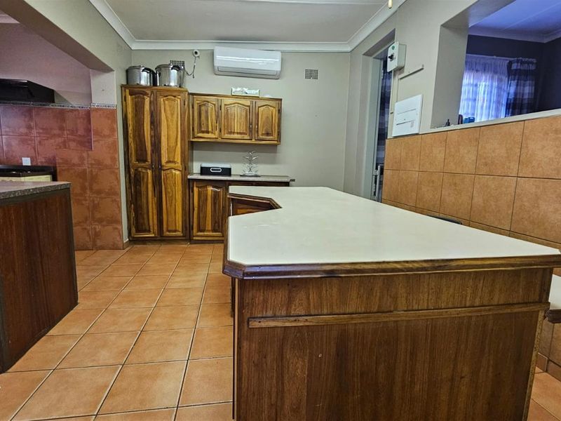 A functional kitchen featuring wooden cabinetry, tiled flooring, and a central breakfast bar, offering a practical layout with potential for modern updates.