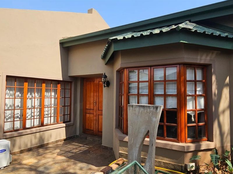 Front entrance area featuring a timber bay window, solid wood door, and paved patio space with an installed air conditioning unit.