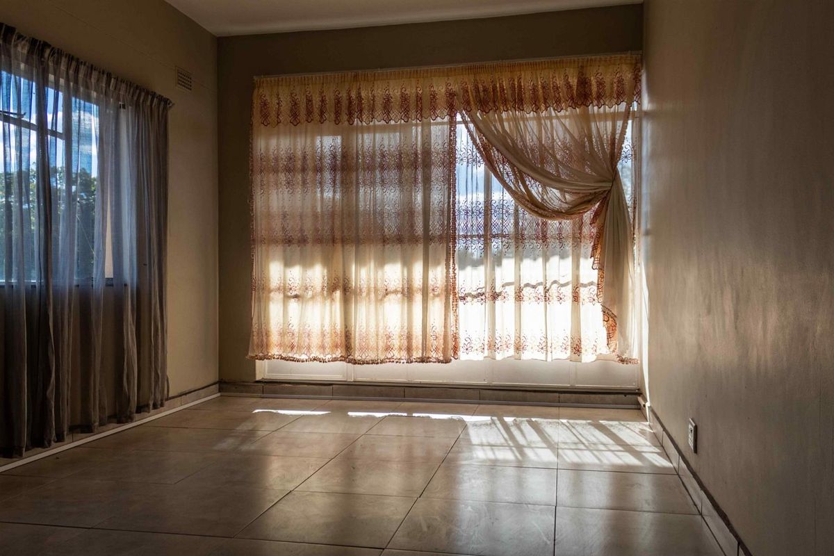 A bright, empty living room featuring tiled flooring and large windows, offering a blank canvas for interior design and personalization.