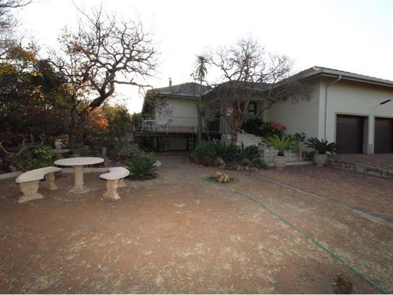 Exterior view of the property featuring a paved driveway, double garage, and a garden area with a raised patio deck.