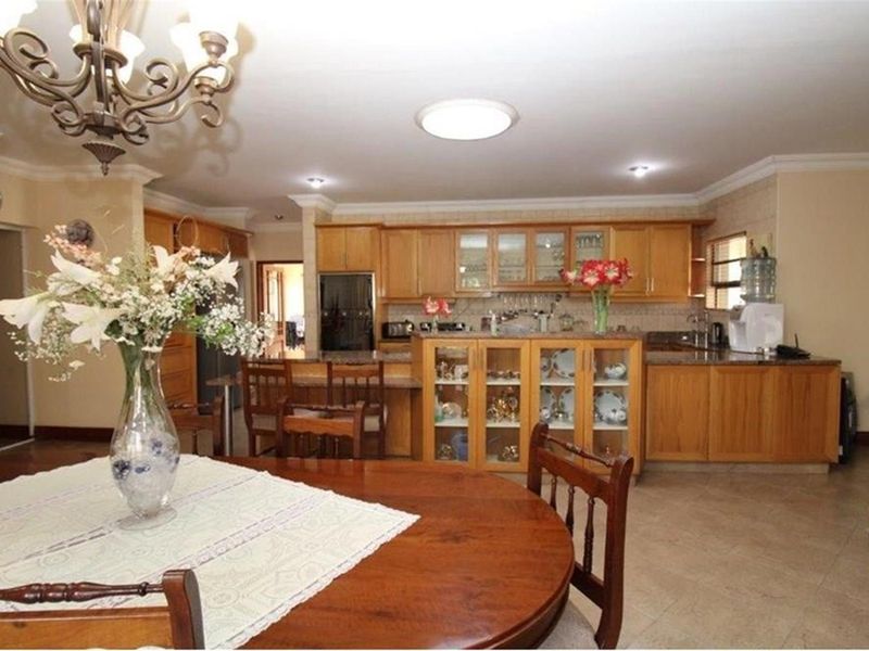 Open plan kitchen and dining area featuring timber cabinetry, granite countertops, and tiled flooring.