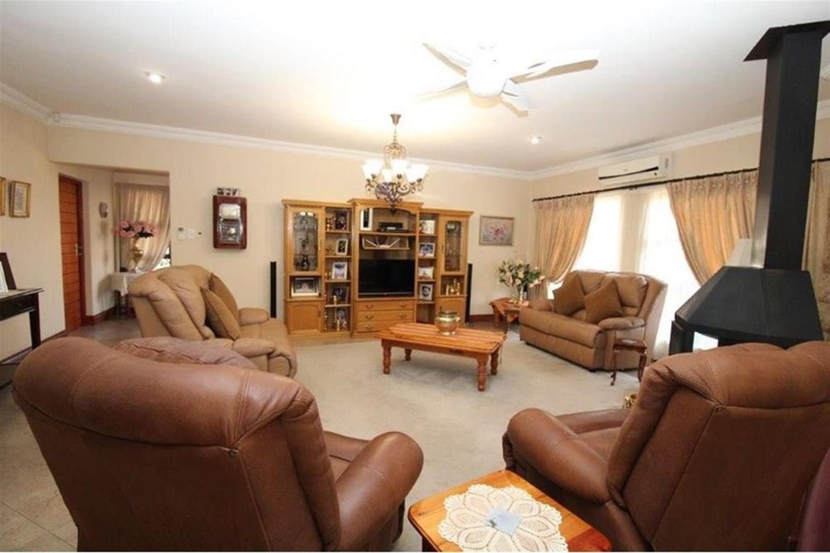 Spacious living room featuring a built-in fireplace, ceiling fan, and wall-mounted air conditioning unit.