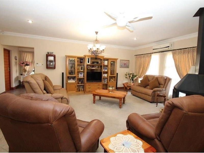 Spacious living room featuring a built-in fireplace, ceiling fan, and wall-mounted air conditioning unit.