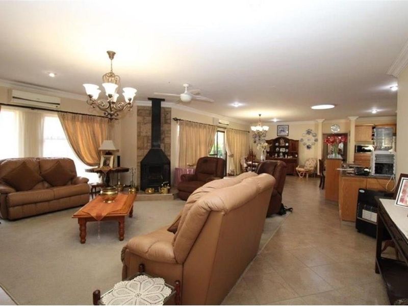 Spacious open-plan living and dining area featuring a stone-clad fireplace, tiled flooring, and integrated kitchen space with neutral finishes.