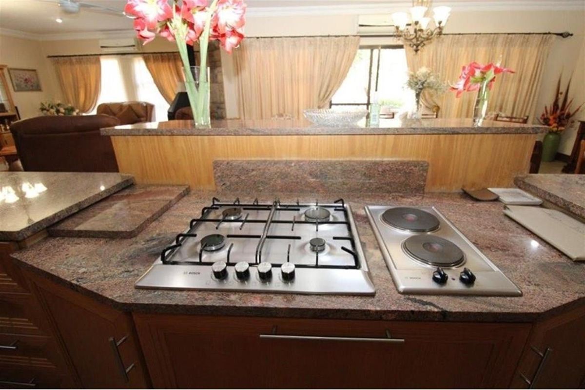Kitchen island featuring a granite countertop with a built-in gas hob and electric hotplate, overlooking the open-plan living area.