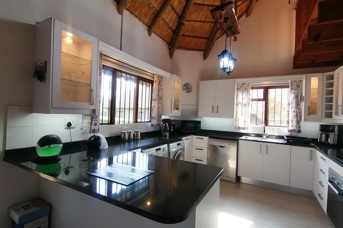A well-appointed kitchen featuring granite countertops, ample cabinetry, and a unique vaulted thatch ceiling, providing a warm and functional cooking space.