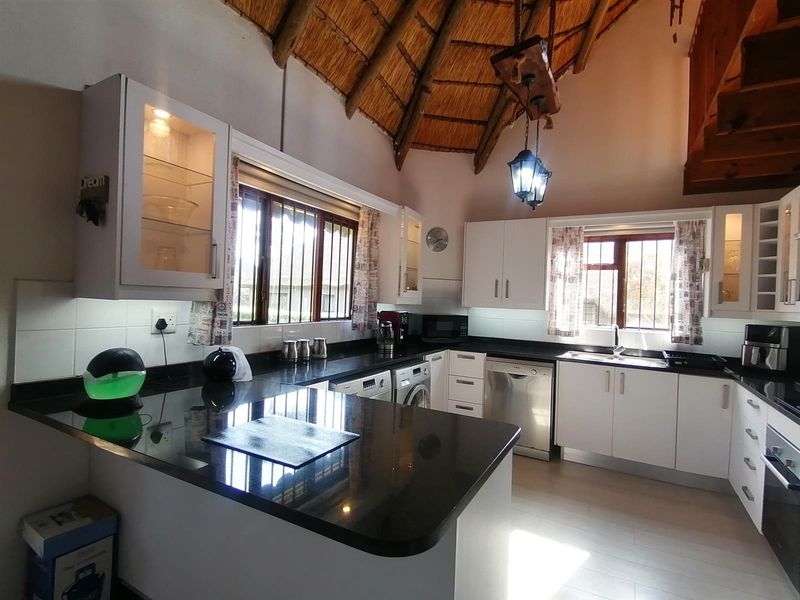 A well-appointed kitchen featuring granite countertops, ample cabinetry, and a unique vaulted thatch ceiling, providing a warm and functional cooking space.