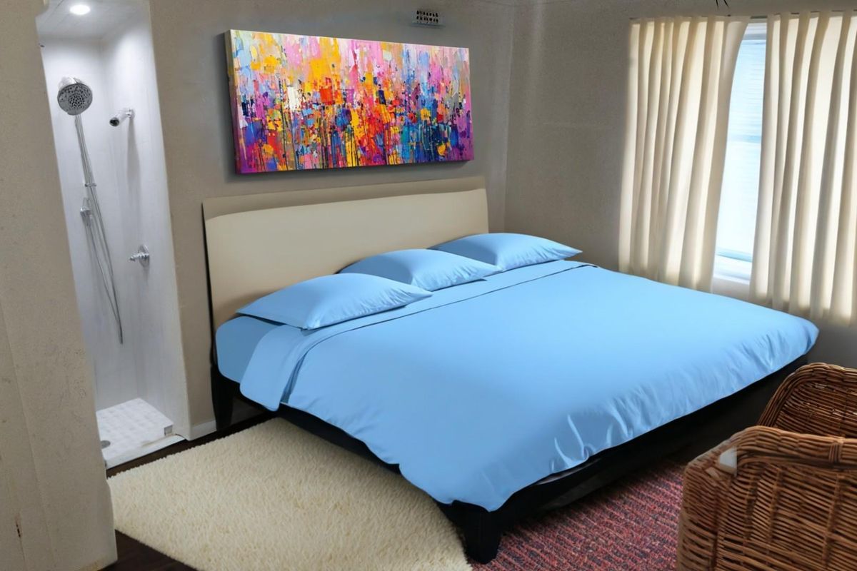 A bedroom featuring an integrated open-plan shower stall, neutral wall finishes, and large windows with curtains.