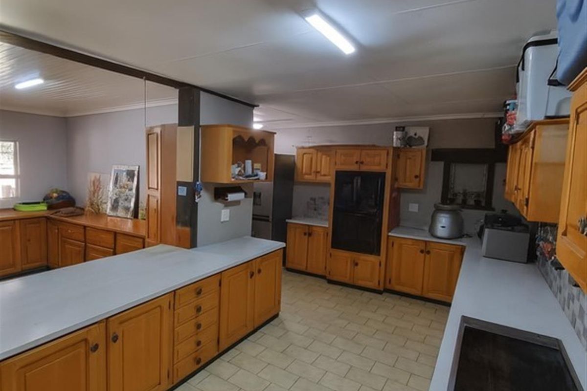 Spacious farm-style kitchen featuring extensive wooden cabinetry, ample countertop workspace, and integrated oven, offering a functional layout for large-scale meal preparation.