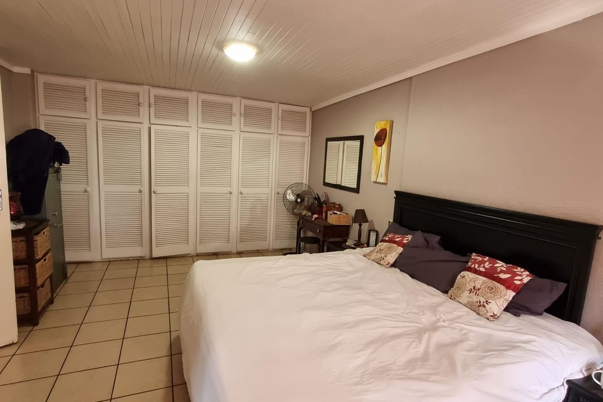 A spacious bedroom featuring extensive built-in louvered-door cabinetry, tiled flooring, and a tongue-and-groove ceiling finish.