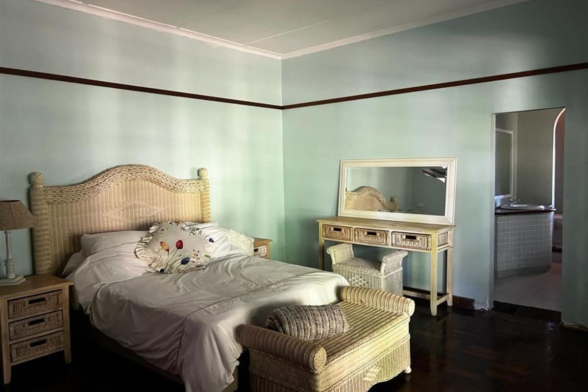 Spacious bedroom featuring dark timber flooring, picture rails, and an adjoining en-suite bathroom.