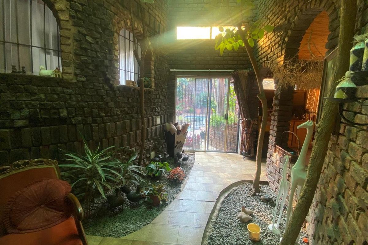 Unique indoor atrium space featuring exposed brick walls, tiled walkway, and integrated garden beds with natural light.