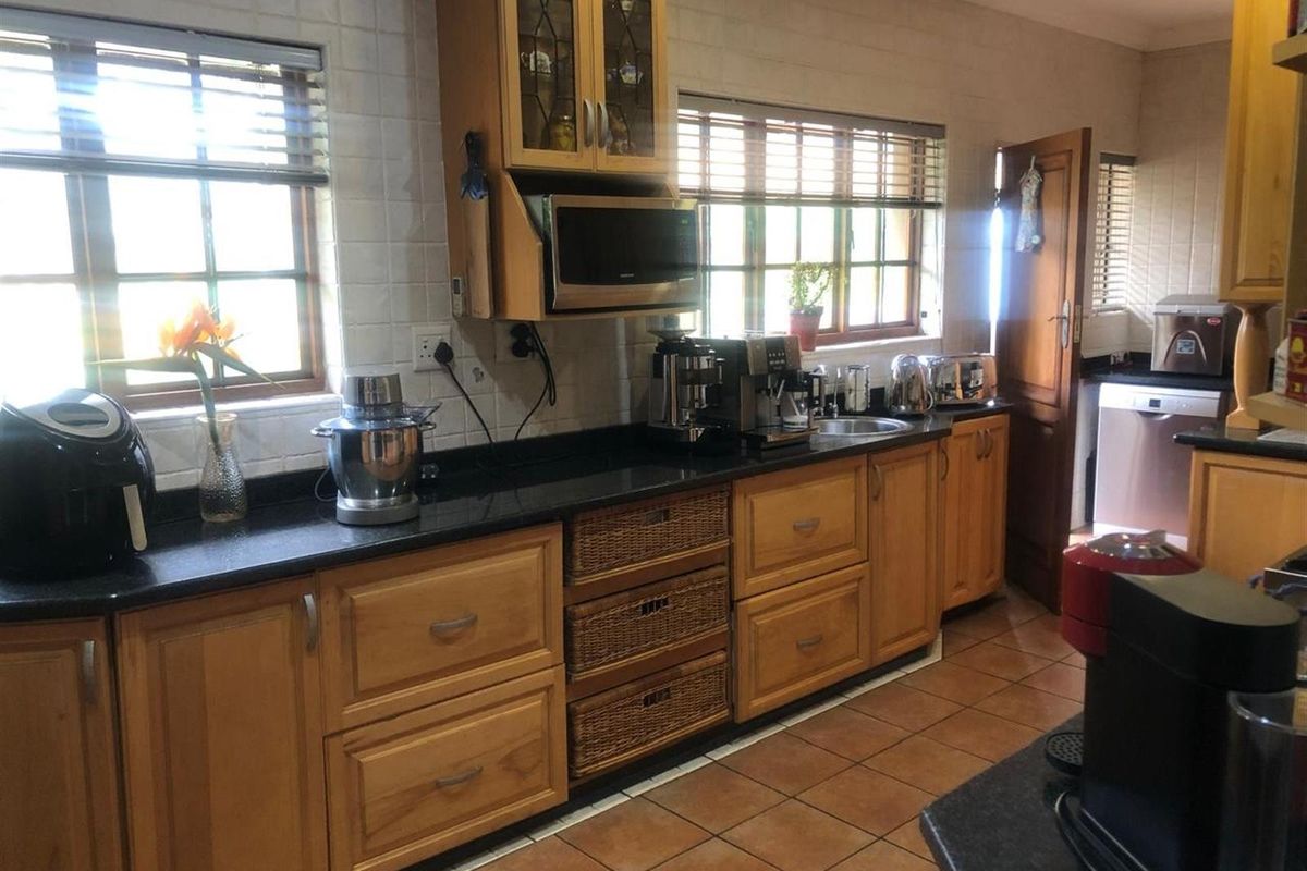 A functional kitchen featuring wooden cabinetry, granite countertops, tiled backsplash, and ceramic flooring, offering ample storage and workspace.